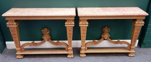 A pair of Louis XIV style console tables, each with faux painted marble tops over a carved bleached mahogany base, with tapering square supports unite
