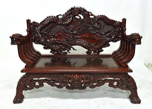 An early 20th century Chinese red lacquer bench, extensively relief carved with dragons chasing pearls, 135cm wide. Illustrated