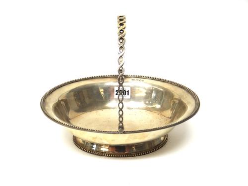 A silver oval cake or fruit basket, decorated with a beaded rim and with a pierced swingover handle, on a beaded oval foot, London 1921, weight 627 gm