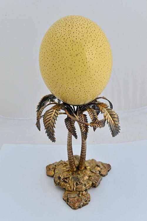 An Elkington & Co plated table centrepiece stand, formed as two palm trees, supporting an ostrich egg, the triform base of rustic form, decorated with