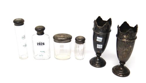 Silver and silver mounted wares, comprising; a lotion bottle, three bottles and jars and a pair of vases, with decorated shaped rims and on loaded bas