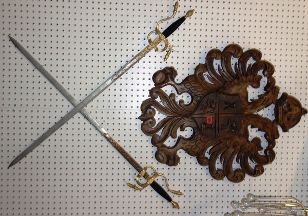 A pair of reproduction Spanish swords together with a carved oak wall mounted coat of arms, (3).DISPLAY
