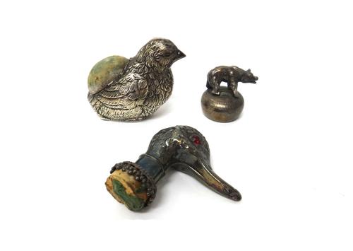 A silver pin cushion, modelled as a bird, Birmingham 1921, a plated bottle cork mount, modelled as the head of a duck with red paste set eyes and a pl