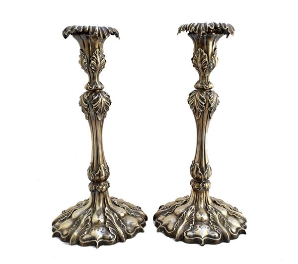 A pair of silver table candlesticks, each with a tapered stem, having foliate decoration, a detachable sconce and raised on a shaped circular foliate