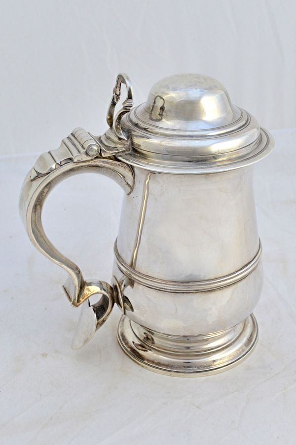 A George III silver hinge lidded tankard, of baluster form with a scrolling handle, having a heart shaped terminal and with an openwork thumbpiece, Lo