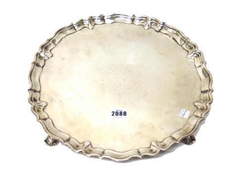 A George II silver salver, of shaped circular form, having a pie-crust rim in the Chippendale style, engraved with a coat of arms to the centre and ra