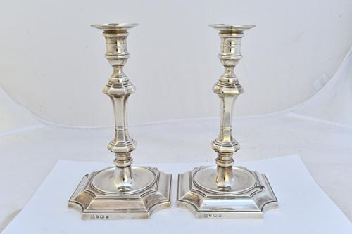 A pair of silver table candlesticks, each with a tapered squared stem, with a detachable sconce and raised on a cut cornered square base, in an 18th c