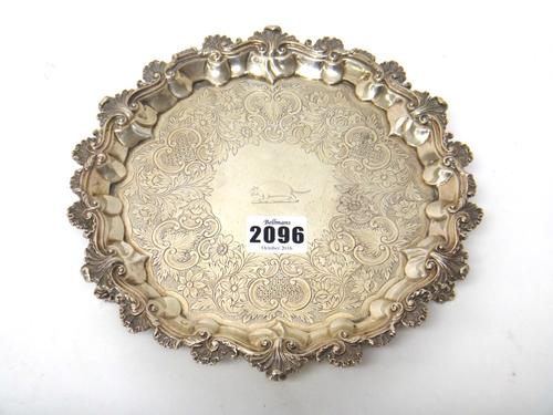 A silver salver, of shaped circular form, with pie crust rim, enhanced with a cast scroll and scalloped border, otherwise with engraved decoration, cr
