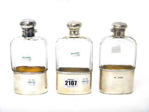 Three silver mounted faceted glass spirit flasks, with pull-off beaker silver beaker bases, London 1906, London 1903 and London 1915, (3).