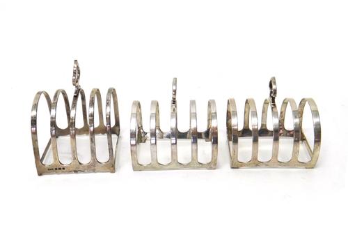 A pair of silver five bar toastracks, with loop shaped handles, Sheffield 1962 and another silver five bar toastrack, with a loop shaped handle, Birmi