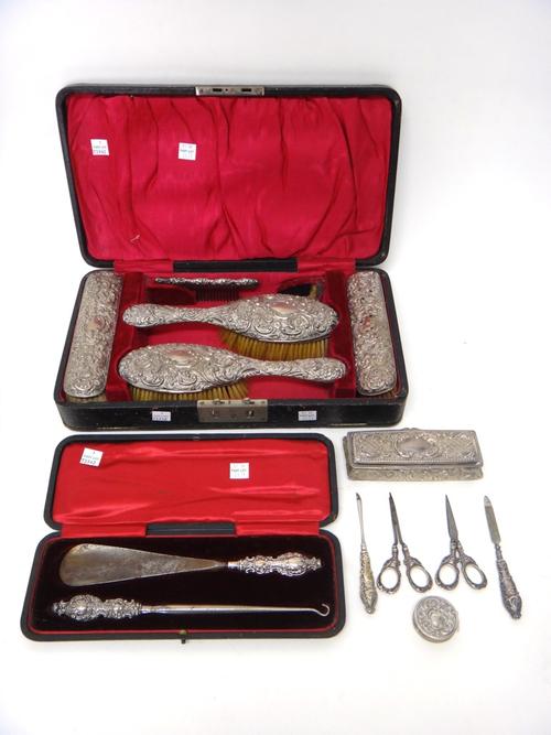 Silver and silver mounted wares, comprising; two hairbrushes, two clothes brushes and the remains of a comb, with embossed decoration, cased, a button
