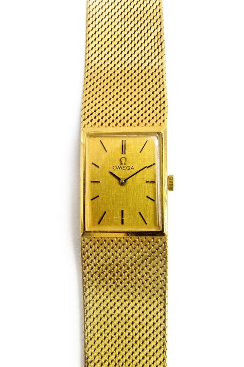 An Omega 18ct gold rectangular cased bracelet wristwatch, the signed rectangular gilt dial, with baton shaped numerals and with black hands, on a tape