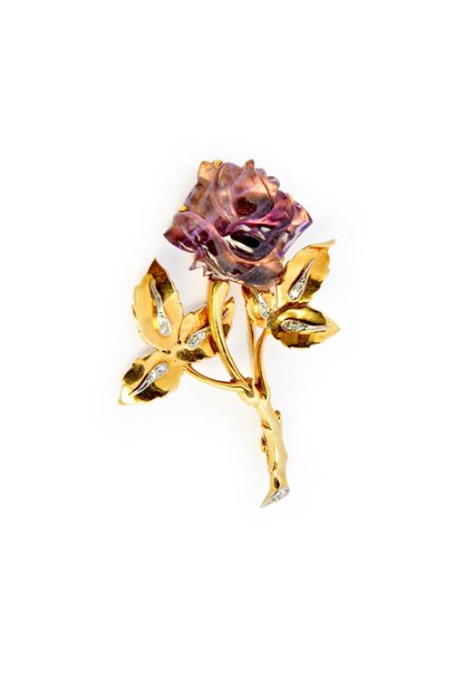 A gold, diamond and carved amethyst brooch, designed as a floral spray, the flowerhead formed from a carved amethyst, the leaves mounted with pairs of