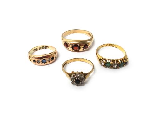 A 9ct gold and garnet set three stone ring, an 18ct gold, green and colourless gem set half hoop ring, Chester 1904, a 9ct gold, sapphire, diamond and