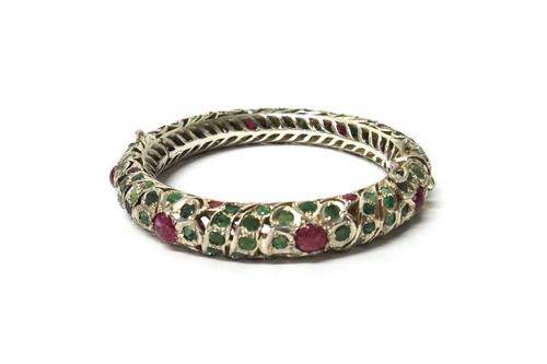 An Eastern cabochon ruby and emerald set circular hinged bangle, with a box.