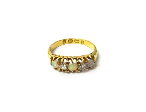 A Victorian 18ct gold, opal and diamond set five stone ring, mounted with three circular opals and with two cushion shaped diamonds mounted at interva