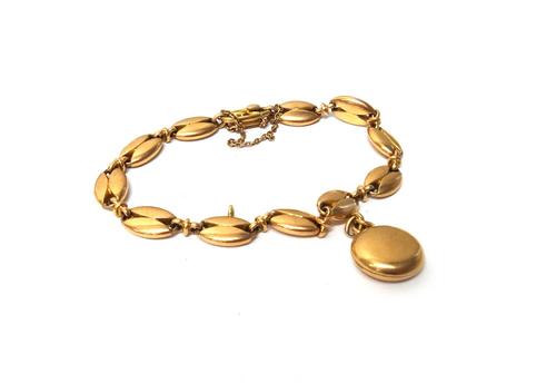 A gold bracelet, in a pierced oval link design, fitted with a gold circular pendant locket and on a snap clasp, detailed 15, fitted with a safety chai