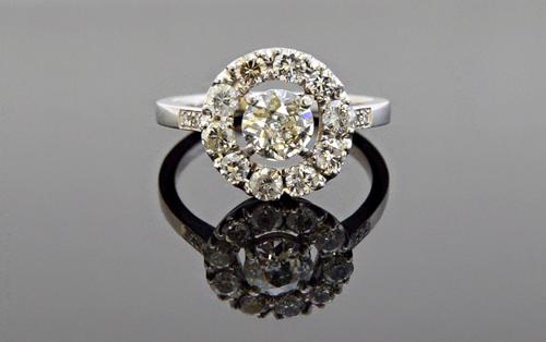 A diamond set cluster ring, claw set with the principal cushion shaped diamond at the centre in an openwork surround, mounted with circular cut diamon