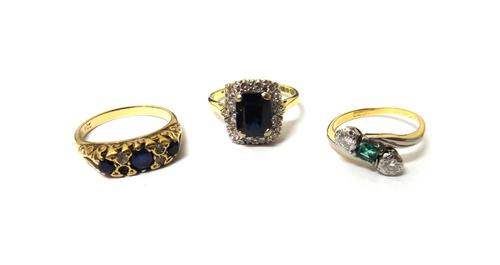An 18ct gold, sapphire and diamond set rectangular cluster ring, Birmingham 1963, a gold and platinum, emerald and diamond set three stone ring, in a