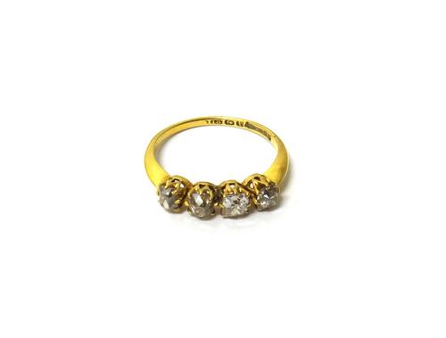 An 18ct gold ring, claw set with a row of four cushion shaped diamonds, Birmingham 1908, ring size P and a half.