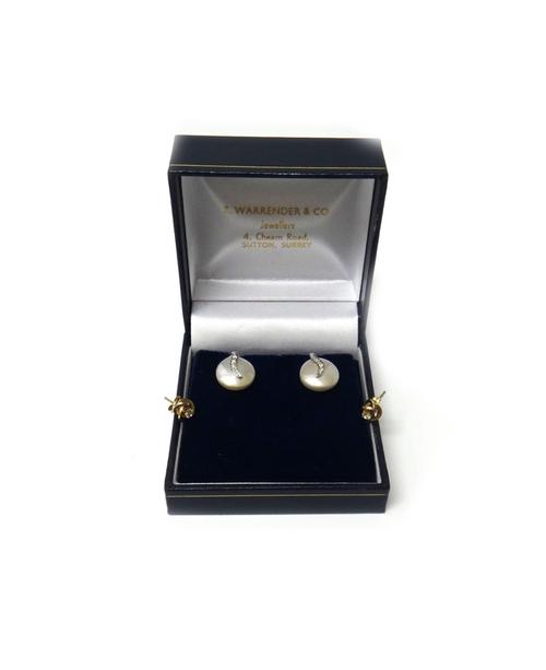 A pair of 9ct white gold, diamond and cultured pearl set earstuds, each with a button shaped cultured pearl and with a diamond set four stone motif, t