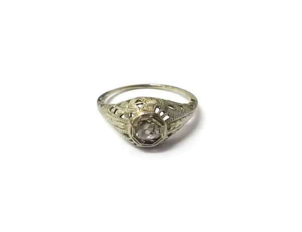 A white gold and diamond set single stone ring, mounted with a cushion shaped diamond, the mount with pierced and engraved floral decoration, ring siz