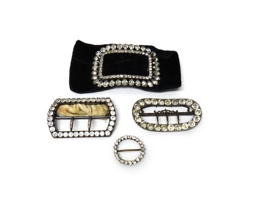 Four colourless paste set jewels, comprising; a curved oval buckle, a curved rectangular buckle, a small circular slide and a large curved rectangular