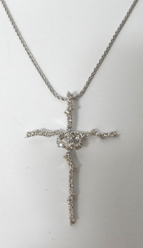 A diamond set pendant cross, in a rustic design, mounted with circular cut diamonds, on a white gold neckchain, detailed 750, with a sprung hook shape