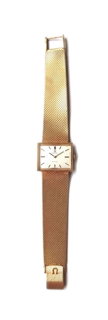 A gold Omega De Ville bracelet wristwatch, the signed rectangular silvered dial with baton shaped numerals, on a tapering woven mesh link bracelet, wi