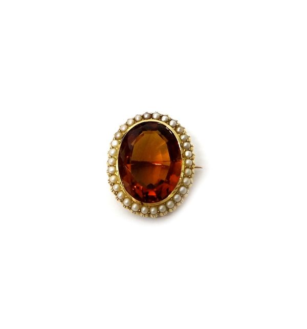A gold, citrine and seed pearl set oval brooch, mounted with the oval cut citrine at the centre, in a surround of seed pearls, circa 1910. Illustrated