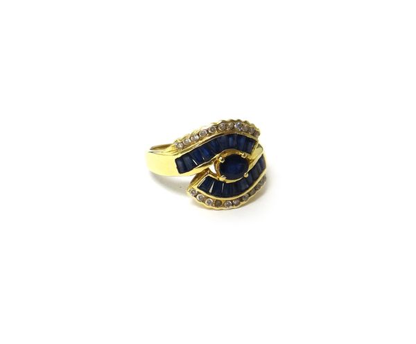 A gold, sapphire and diamond set ring, mounted with the principal oval cut sapphire at the centre, between sapphire set serpentine sides and bordered