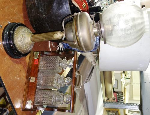 A silver plated three bottle tantalus and an oil lamp with shade (2).  DIS