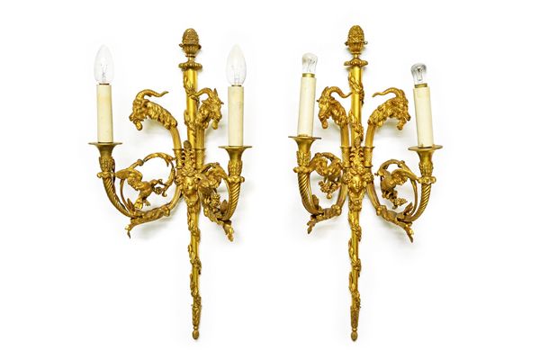 A pair of French ormolu twin light wall appliques, 20th century, each with central tapering backplate with foliate finial and banding, issuing two spi