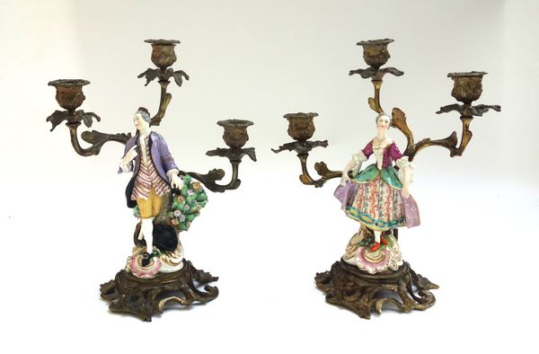 A pair of bronze and porcelain mounted figural three branch candelabra, 19th century, the porcelain probably Derby, modelled as a gallant and companio