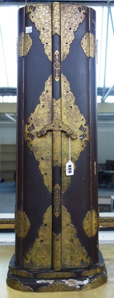 A Chinese lacquered papier mache shrine, circa 1900, the case decorated all over with brass foliate engraved embellishments, the bi-fold twin doors op
