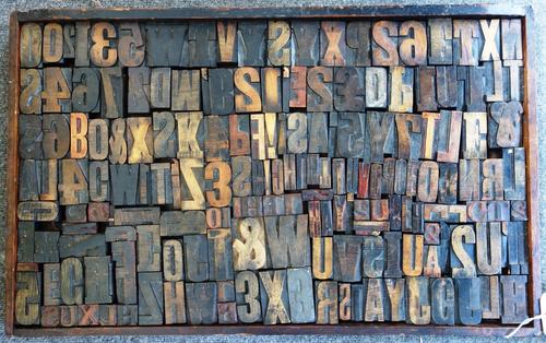 A quantity of wooden printers blocks, early 20th century, alphabet and numerical, contained in a rectangular wooden tray, 86cm x 54cm.