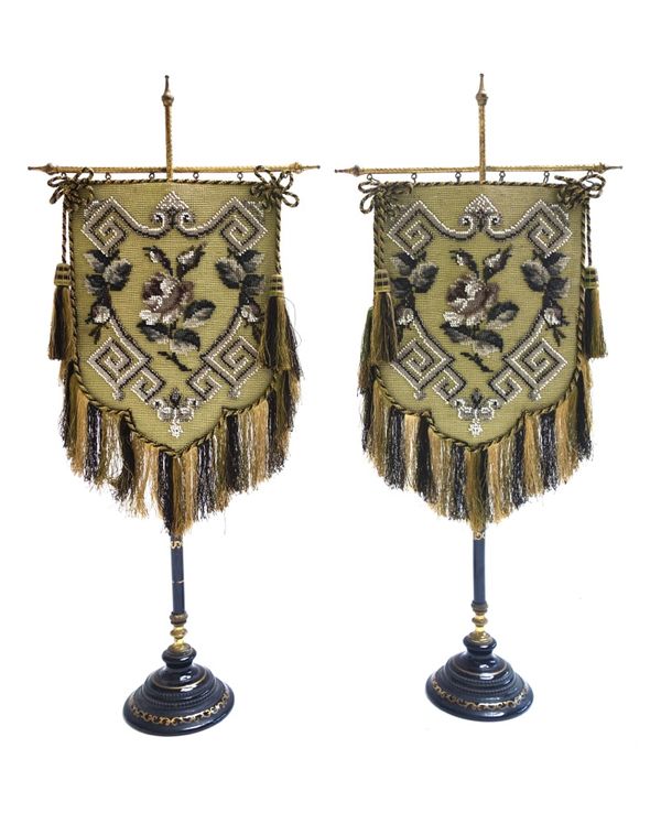 A pair of porcelain and metal mounted table banners, late 19th century, with foliate beadwork panel over a gilt and ebonised stem and circular foot, 5