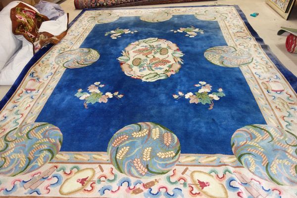 A Chinese carpet, the plain indigo field with a central ivory roundel of vegetables and eight circles with grass and wheat sprays, an ivory border wit
