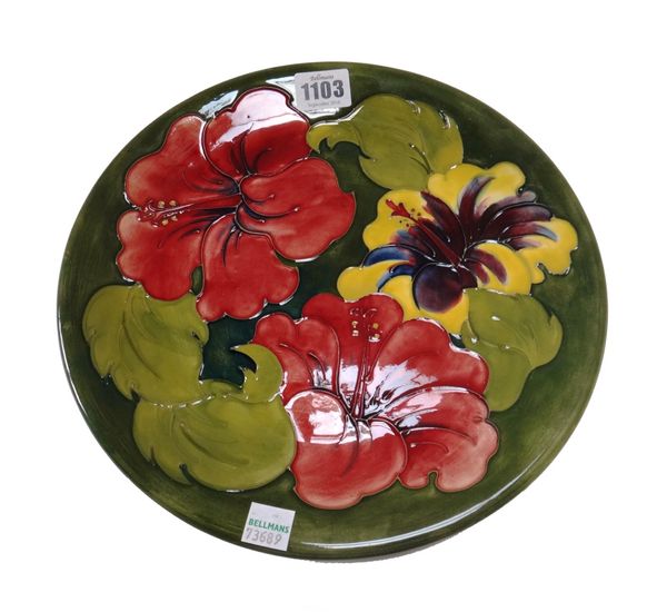 Four Moorcroft green ground plates, circa 1930, two hibiscus and two anemone, with impressed and painted marks, 26cm diameter. (4)