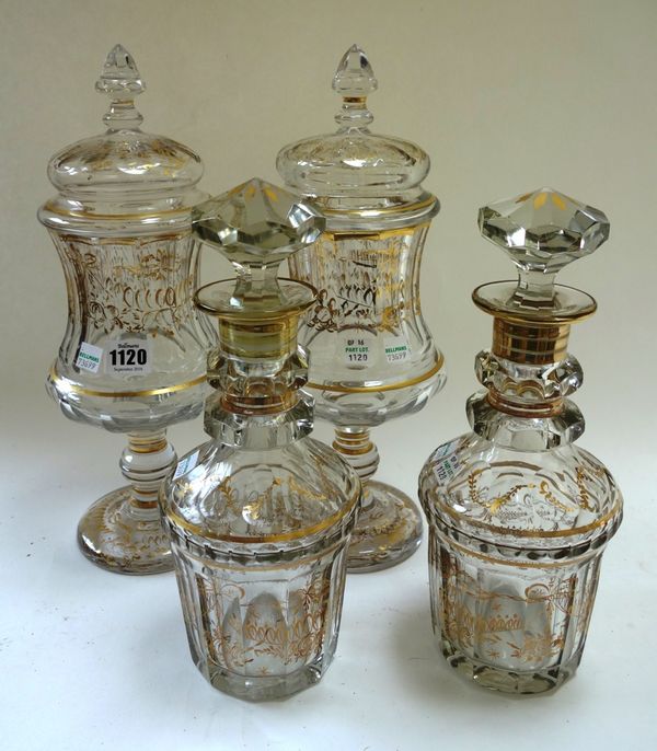 A pair of Continental glass jars and covers, early 20th century, with gilt foliate decorated against a pinched waist ground on a knopped pedestal foot