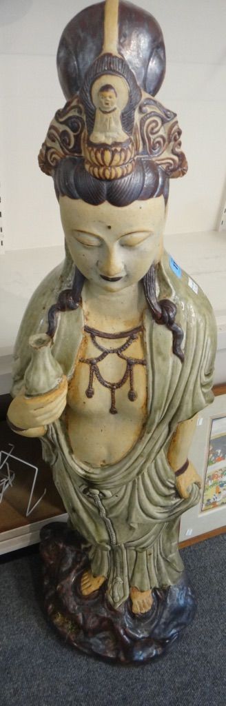A large Chinese stoneware figure of Guanyin, 20th century, standing on a rocky mound holding a flask in her left hand, 110cm.high.