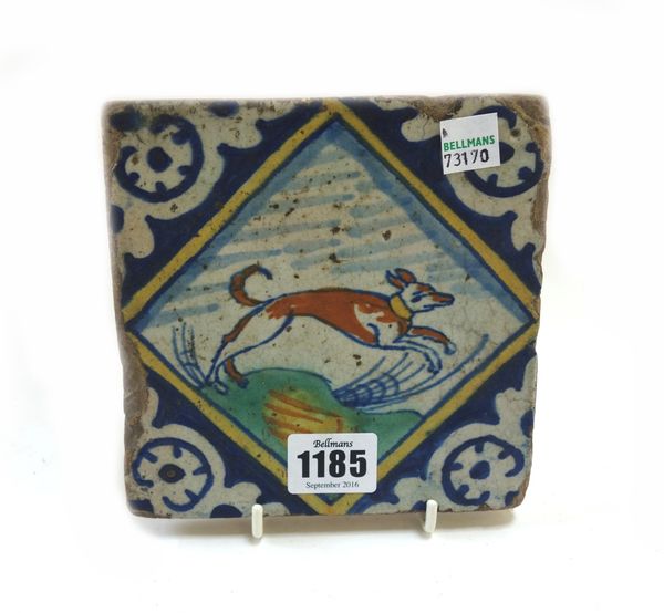 A Dutch Delft polychrome tile, early 17th century, painted with a leaping dog in a landscape, (a.f), 14cm.