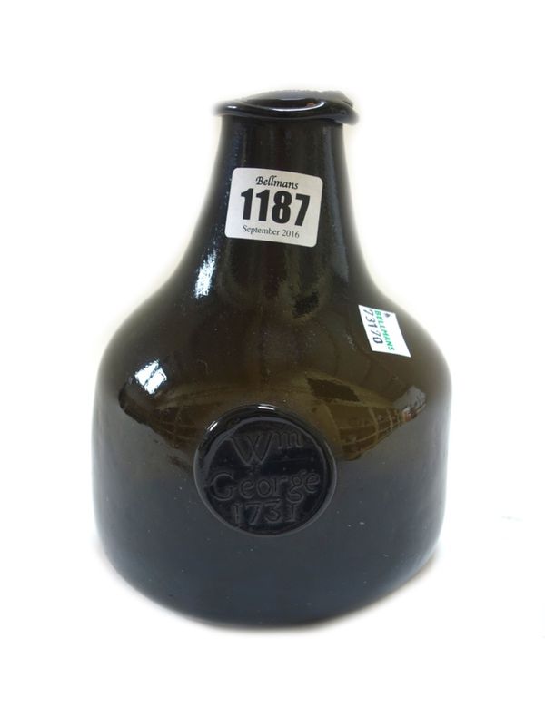 An English olive green glass sealed wine bottle, dated 1731, of mallet form, bearing the seal inscribed `Wm George 1731, (a.f), 17cm. high