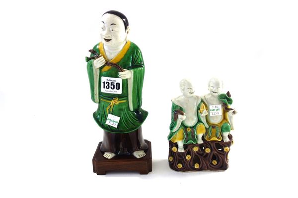 A Chinese famille-verte biscuit figure of a man, probably Kangxi, standing holding lotus flowers, 22cm.high, wood stand; and a biscuit group of the `h