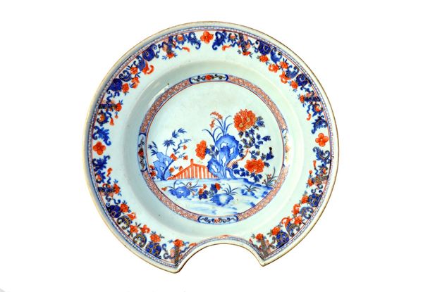 A Chinese Imari barber's bowl, circa 1720-50, painted in underglaze-blue, iron-red and gilding with a central panel enclosing a fenced garden with flo
