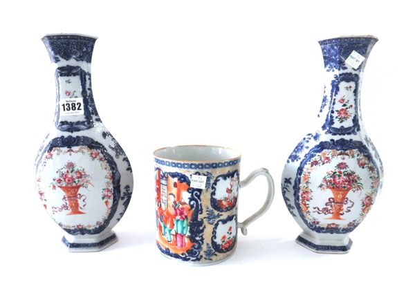 A pair of Chinese famille-rose hexagonal baluster vases, Qianlong, each enamelled with vases of flowers inside underglaze-blue borders, (a.f), 29.5cm.