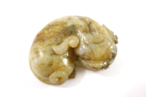 A Chinese jade carving of a buddhist lion, 19th/20th century, in recumbent pose with head resting on its front paws, 6cm. wide.