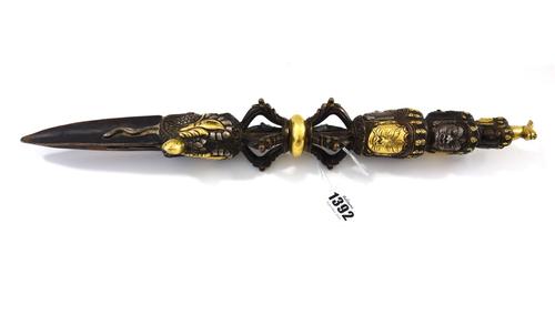 A large Tibetan bronze ritual phurba, possibly late 19th century, the handle fashioned as three graduating tiers of tantric masks higlighted in gilt-b