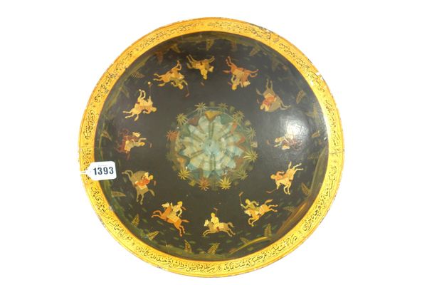 A Persian black lacquer shallow bowl, late 19th century, painted with a band of polo players encircling a central landscape medallion, the border with