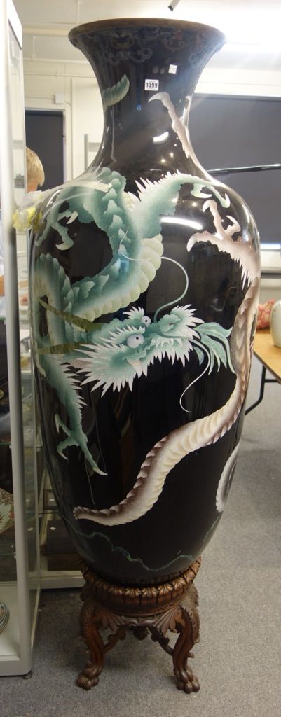 A very large Japanese cloisonné vase, 20th century, worked with dragons on a black ground, with blue painted interior, on a carved wood triform base (